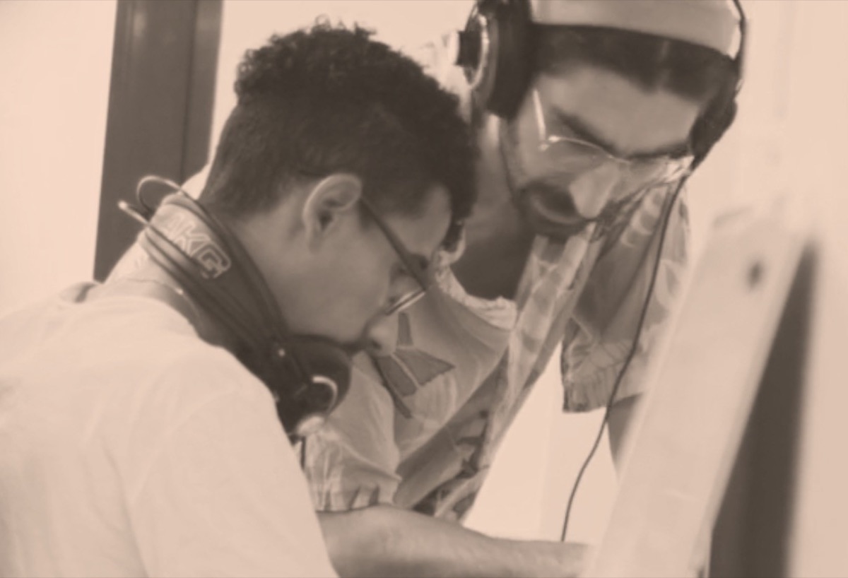 Salih working with a participant in a music studio, both wearing headphones